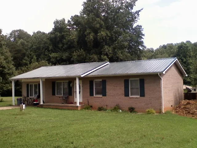 Gray metal roof on a brick ranch house with a side carport in Allegan