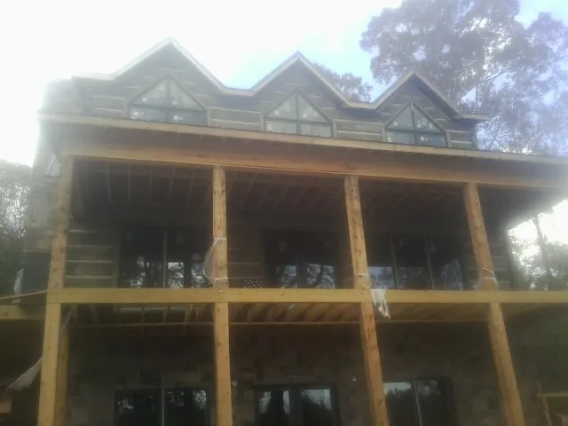 Dormers and porch framing on a large log home under construction — Roof Coating work by our crew in Allegan