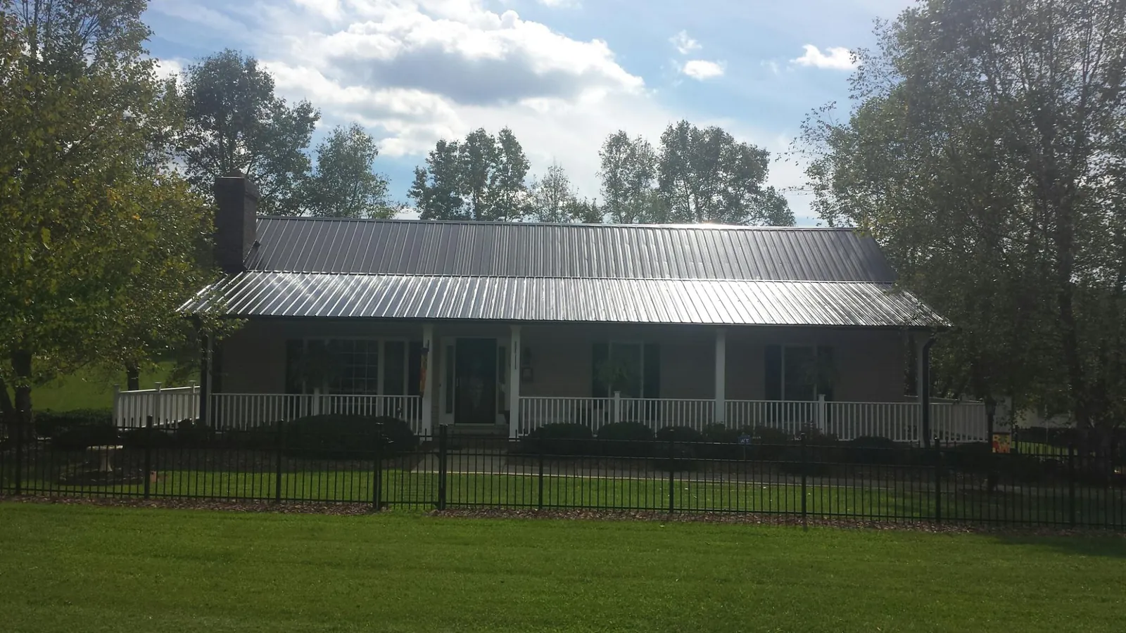 Gray metal roof on a brick ranch with a full width front porch — Gutter Guard Installation work by our crew in Allegan