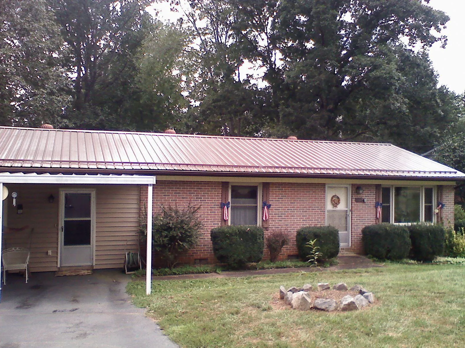 Bronze metal roof and carport on a brick ranch home — Roof Repair work by our crew in Allegan
