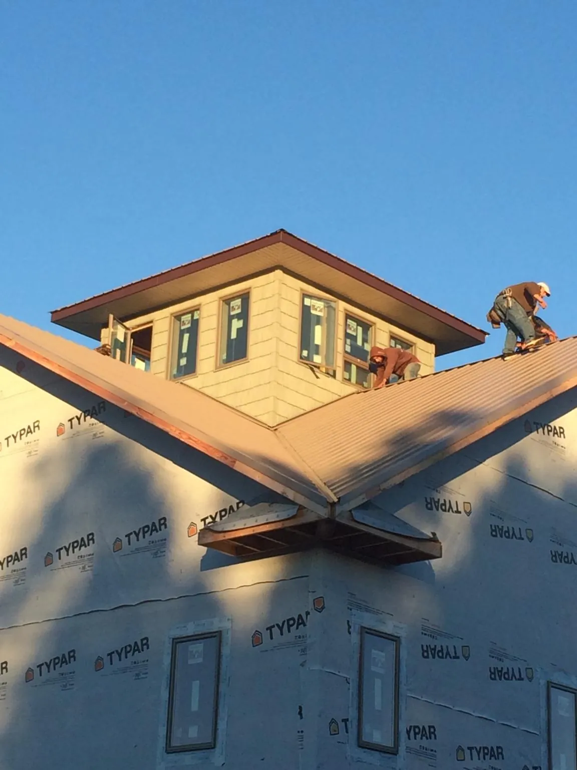 Roofers working around a rooftop cupola on a new metal roof at sunset — Roof Waterproofing in Allegan by Roofing Brothers